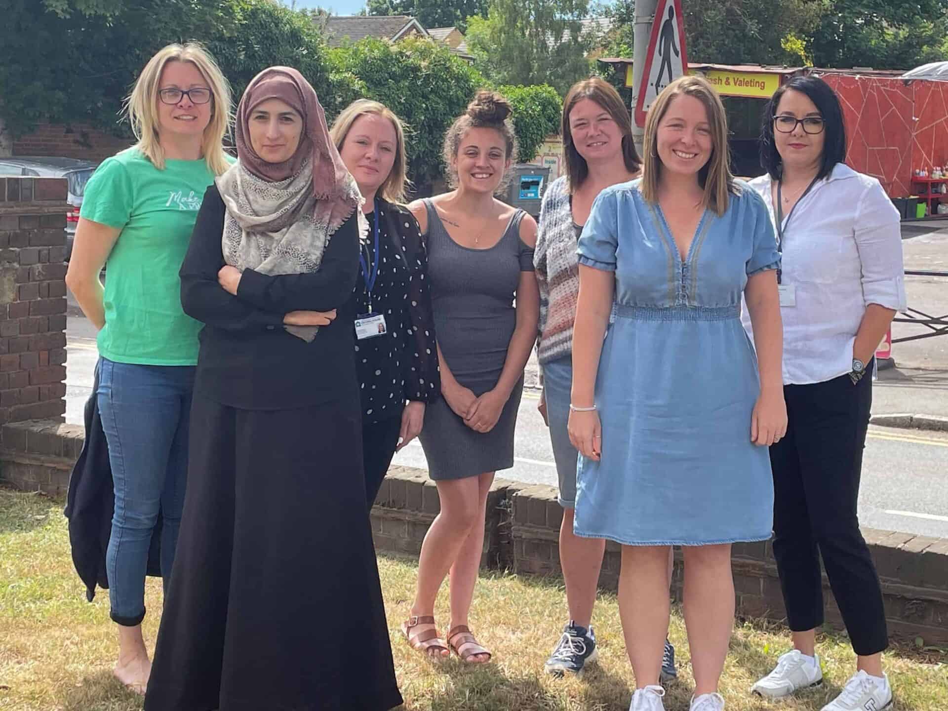 A group of diverse women smiling and posing together outdoors on a sunny day.
