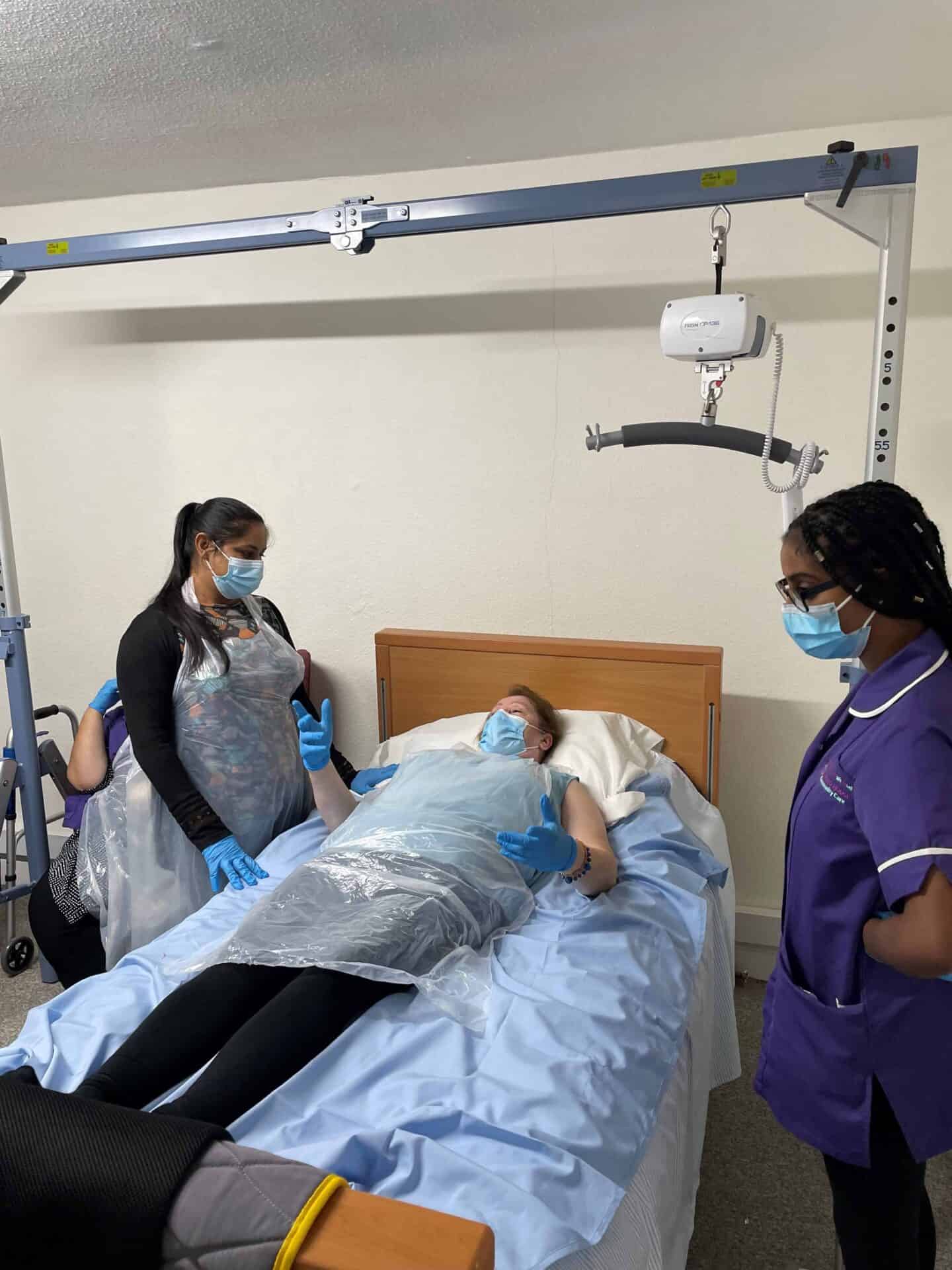 Two healthcare professionals attending to a patient in a hospital bed, all wearing protective face masks.
