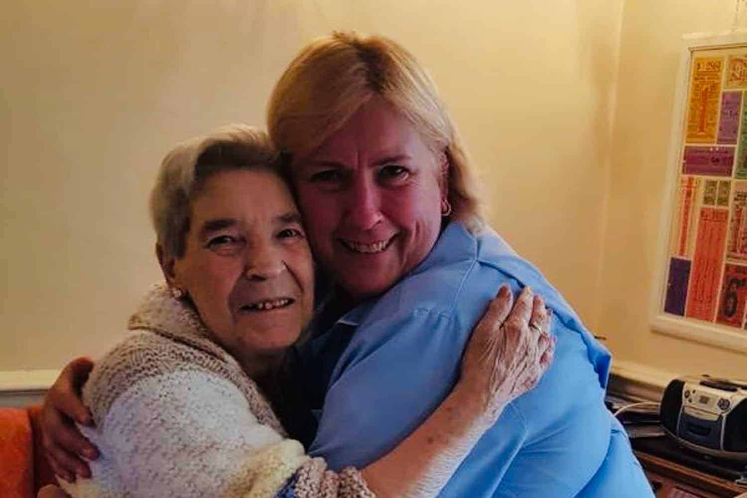 A heartfelt embrace between two women who meet us, likely sharing a moment of joy or comfort.
